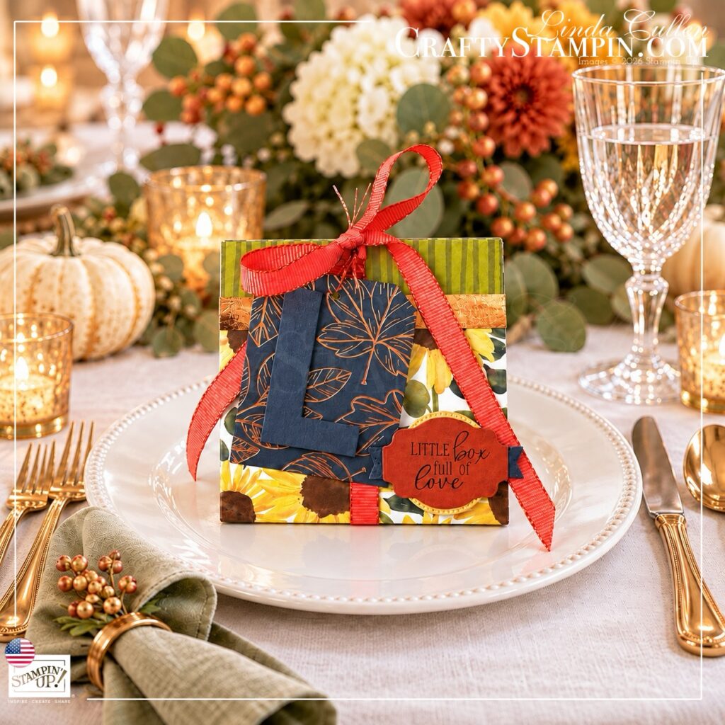 Personalized Thanksgiving tea box with a navy monogram tag and coral bow on a white dinner plate at an autumn table setting.
